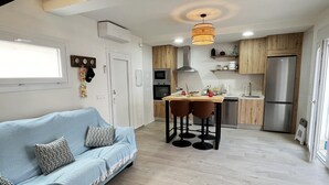 Eine moderne Küche mit Holzausbau, einem Edelstahlkühlschrank, einem Esstisch mit zwei Stühlen und einer Leuchte darüber.