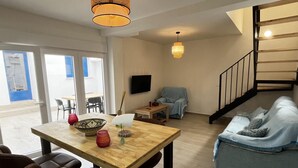 Ein modernes Wohnzimmer mit einem Holzesstisch, zwei Sofas, einer Treppe und einem an der Wand befestigten Fernseher.