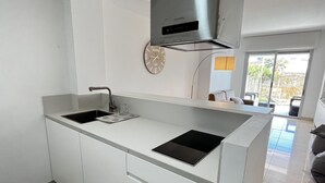 A modern kitchen with a built-in oven, a sink, and a clock on the wall. - Flat Aguamar, ground floor, 1 bedroom, garden and swimming pool. (Dénia)