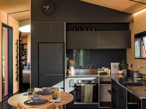 Een moderne keuken met een inbouwoven, een koelkast en een eethoek met een ronde tafel.