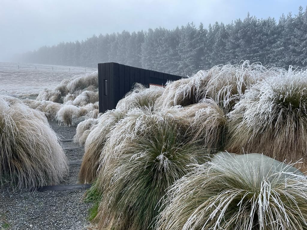 Een landelijk landschap met hooibalen en een houten constructie.