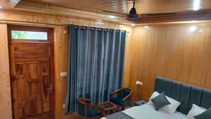 A wooden room with a bed, a chair, a desk, and a curtain.
