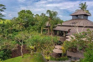 A tropical resort with a thatched-roof main building, a covered outdoor seating area, and lush greenery surrounding the property. - Lumina Sanctuary (Ubud)