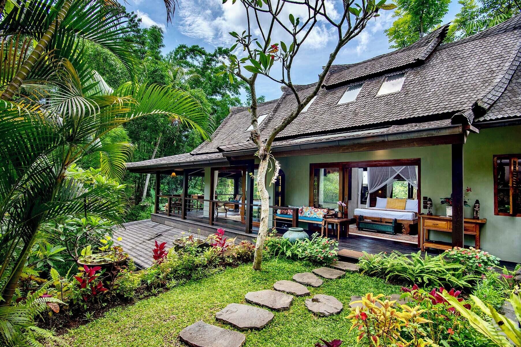 A traditional-style building with a covered porch, a bed with a canopy, and a garden with stone pathways.