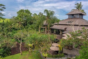 A tropical resort with a thatched-roof structure, lush greenery, and a clear sky.
