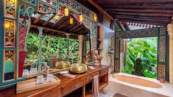 Ein Zimmer mit einem Holznähtisch, einem Spiegel und einer Badewanne.