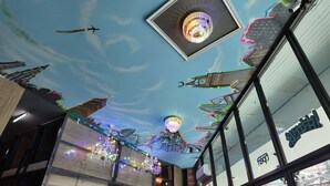 A ceiling with a sky and cloud design, chandeliers, and a clock tower.