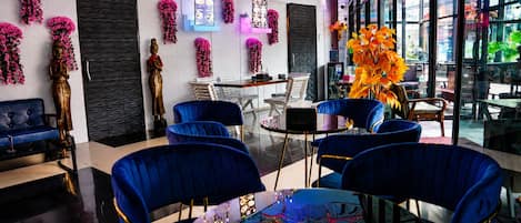 Un interior moderno con sillas azules, una mesa de vidrio y elementos decorativos como flores y cuadros.