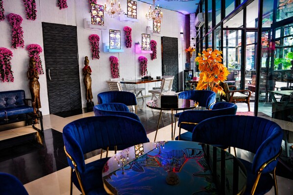 Un interior moderno con sillas azules, una mesa de vidrio y elementos decorativos como flores y cuadros.