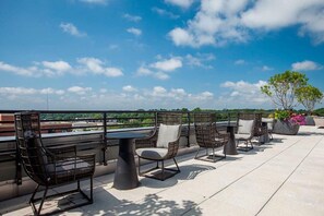 Enjoy a comfortable seating area with wicker chairs and a round table on this rooftop terrace, offering a clear view of the surrounding landscape.