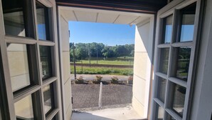 Uitzicht door een deuropening, met een heldere lucht, een spoorlijn en groen op de achtergrond.