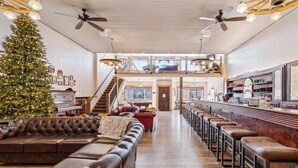 A spacious living room with a large Christmas tree, leather sofas, and a bar area with stools. - Historic Yellowstone Saloon |Sleeps 25, Hot Tub, Pool Table & More! (Ashton)