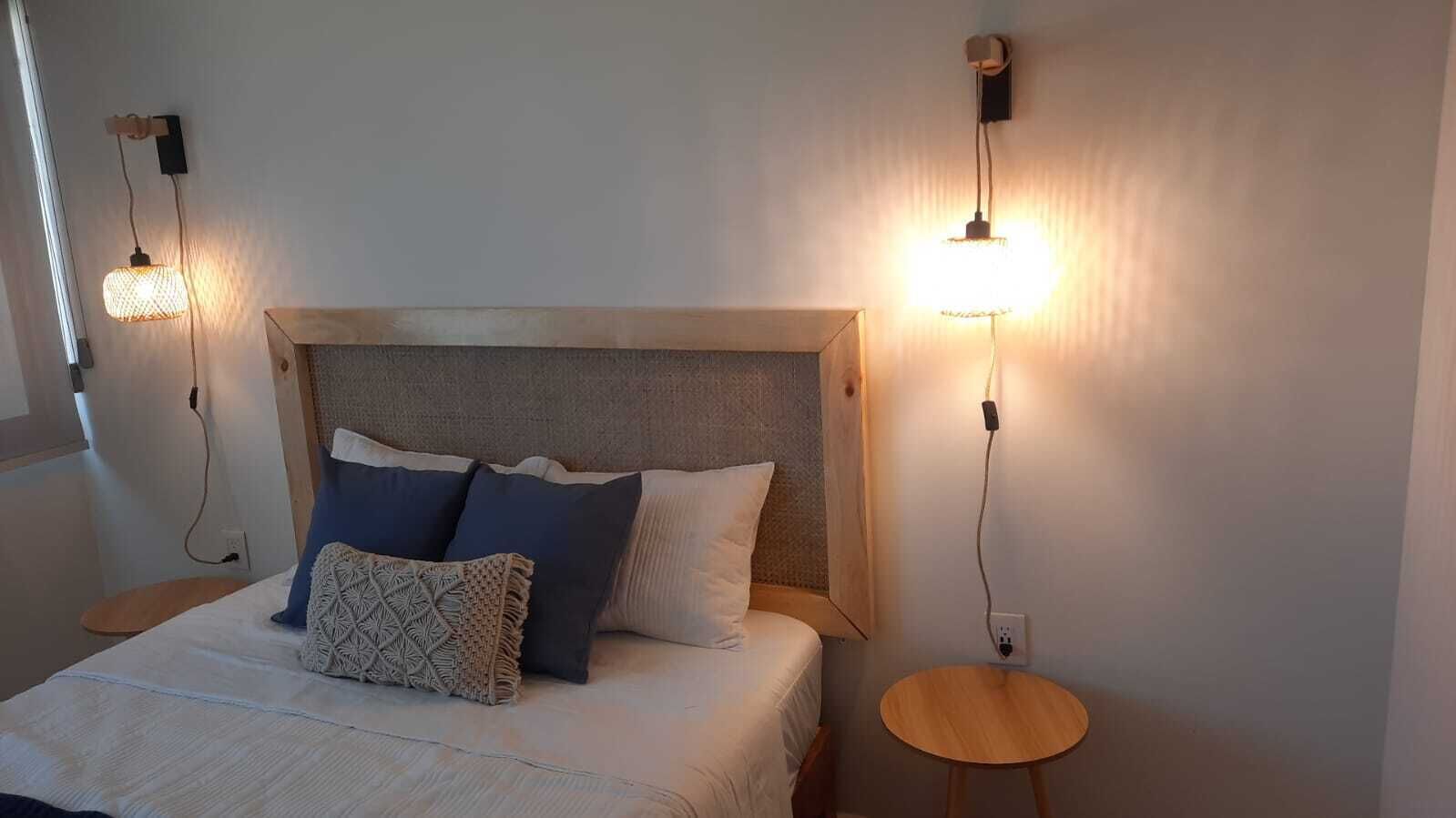 Une chambre à coucher avec un lit, deux tables de chevet et des lampes fixées au mur.