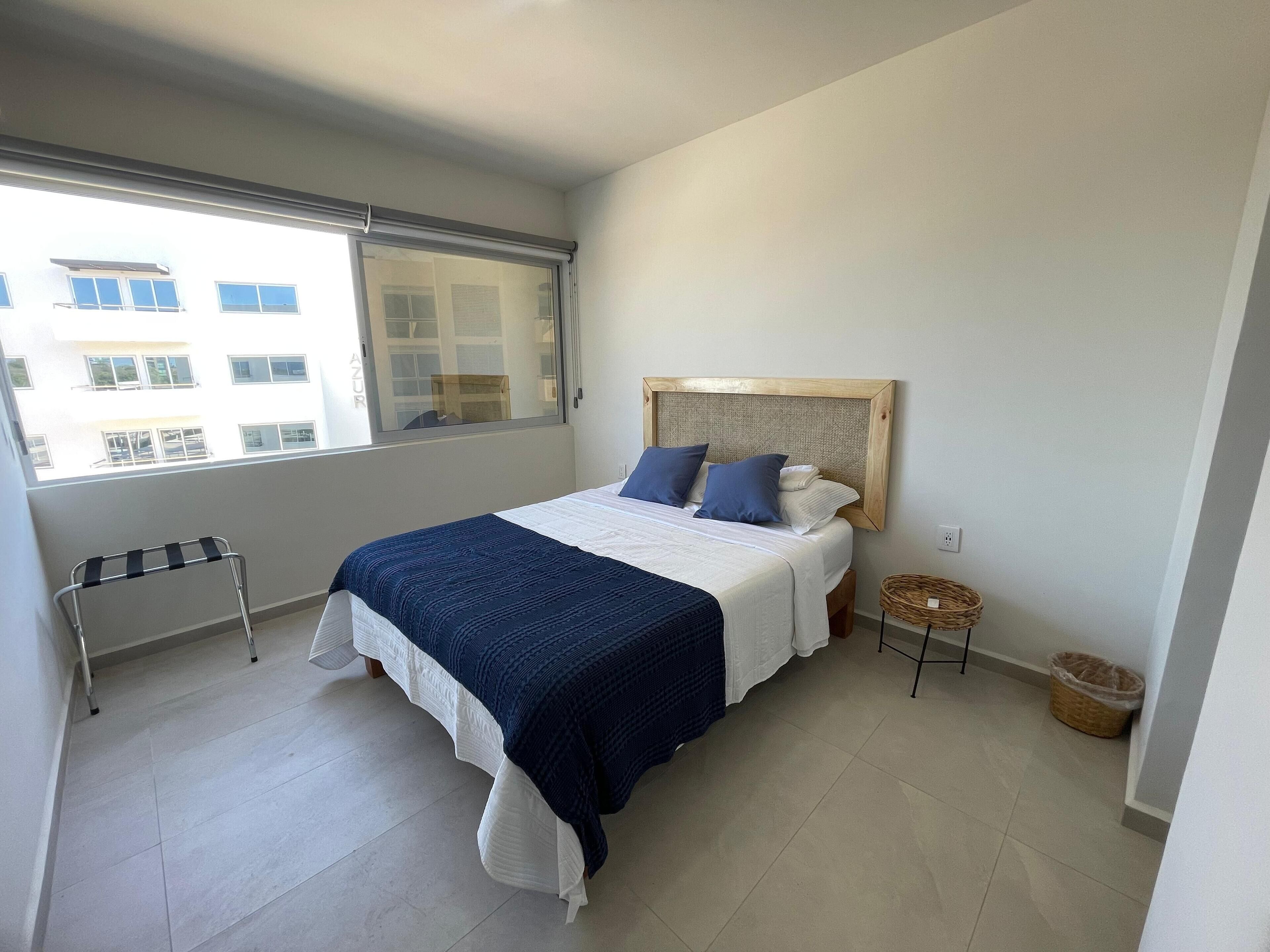 A bedroom with a bed, a window, a radiator, and a small table.
