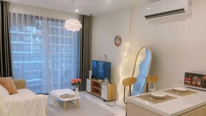 A modern living room with a sofa, TV, and dining area. - Vinhomes Grand Park Luxury Apartments (Ho Chi Minh City)