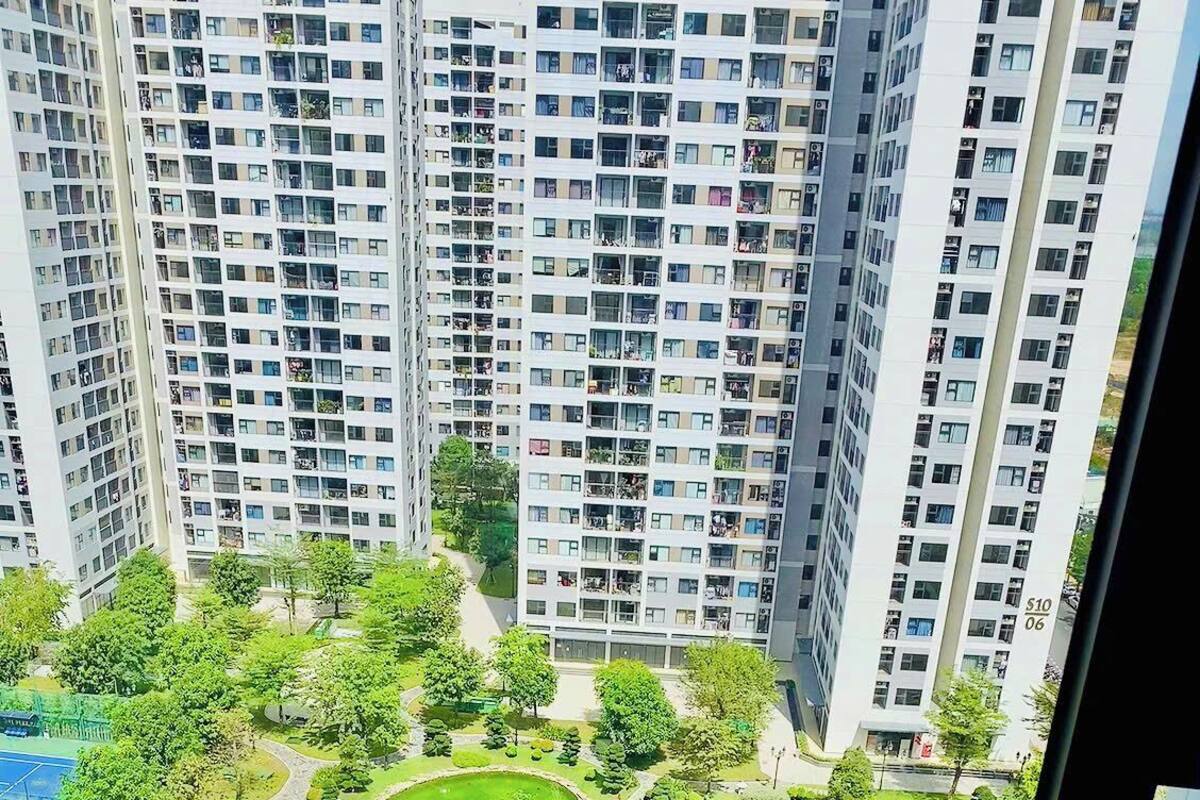 Un edificio residencial de gran altura con varios balcones, un parque ajardinado con piscina y un campo de golf.