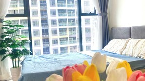 A bedroom with a bed, a window with curtains, and a potted plant. - Vinhomes Grand Park Luxury Apartments (Ho Chi Minh City)