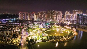 A nighttime view of a cityscape with illuminated buildings and a central park area with a circular water feature. - Vinhomes Grand Park Luxury Apartments  (Ho Chi Minh City)