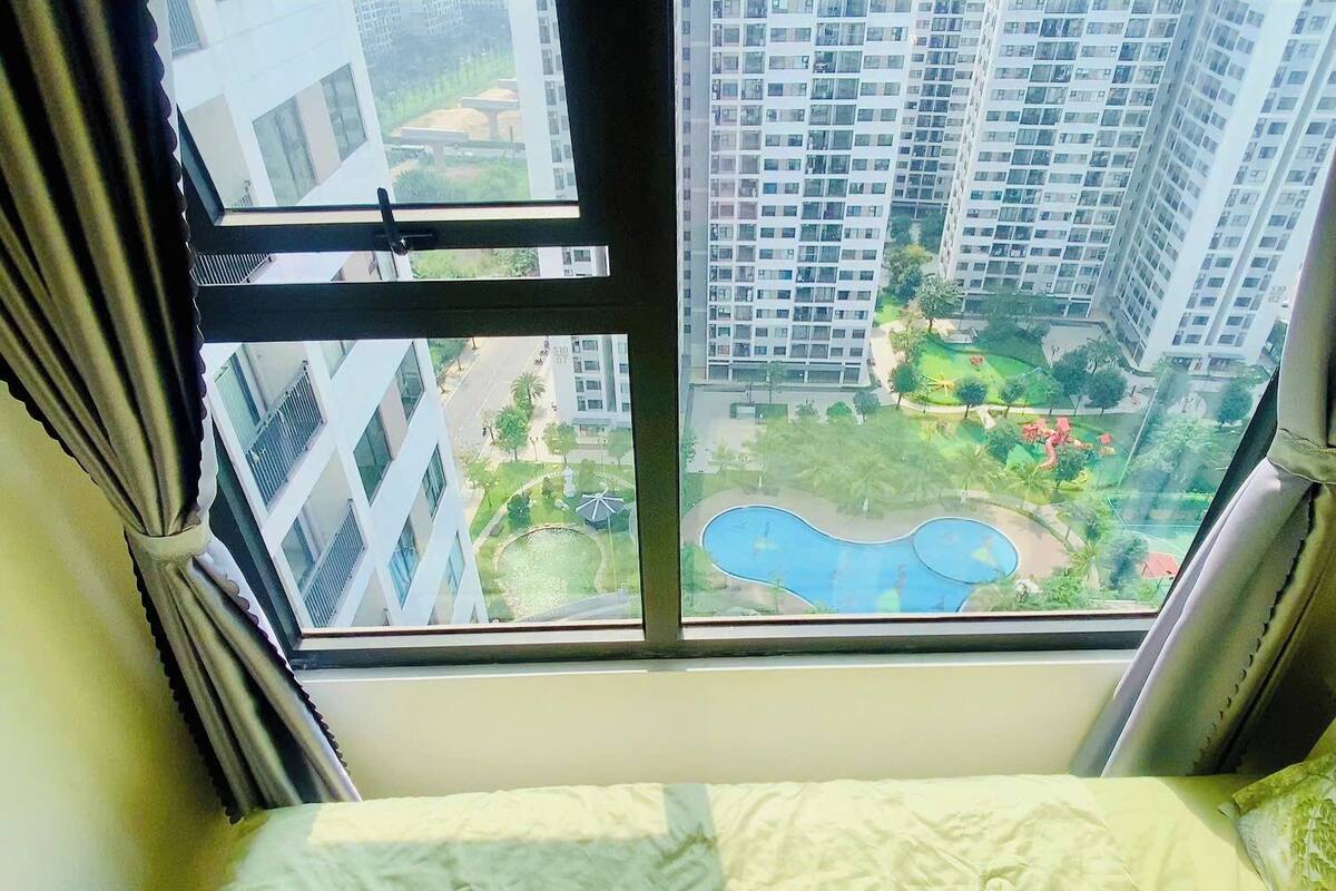 Un dormitorio con vistas a una zona residencial, que incluye edificios altos y una piscina.