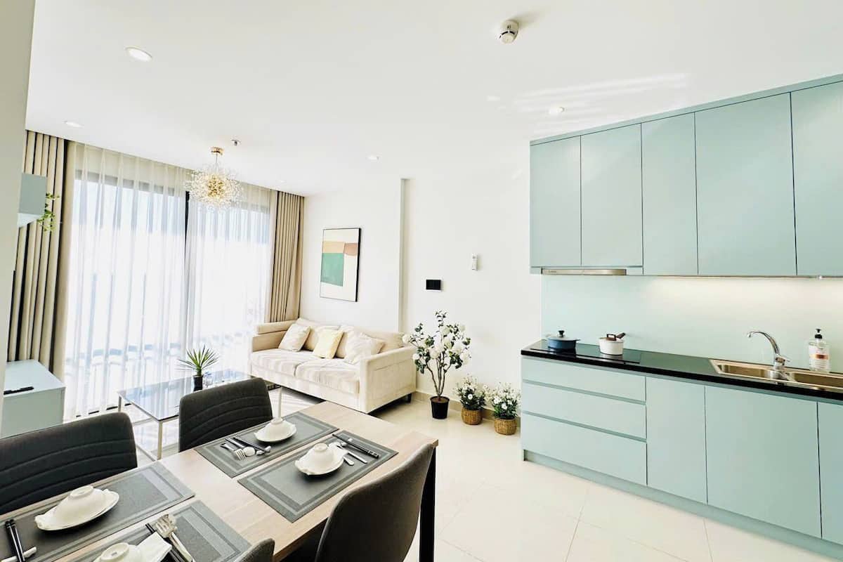 Una sala moderna con sofá, mesa de comedor y zona de cocina con armarios azul claro.