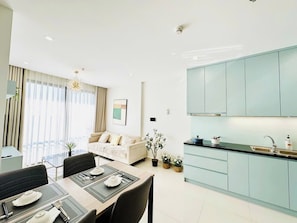 Una sala moderna con sofá, mesa de comedor y zona de cocina con armarios azul claro.