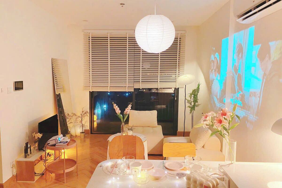 Una sala de estar moderna con comedor, sofá, televisor y un amplio ventanal con persianas.