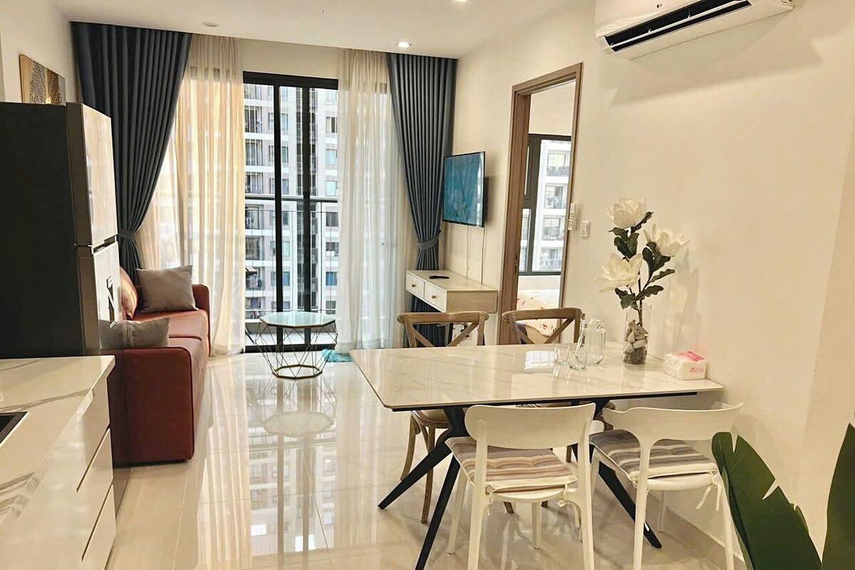 Una sala de estar moderna con comedor, sofá, televisor y un amplio ventanal con cortinas.