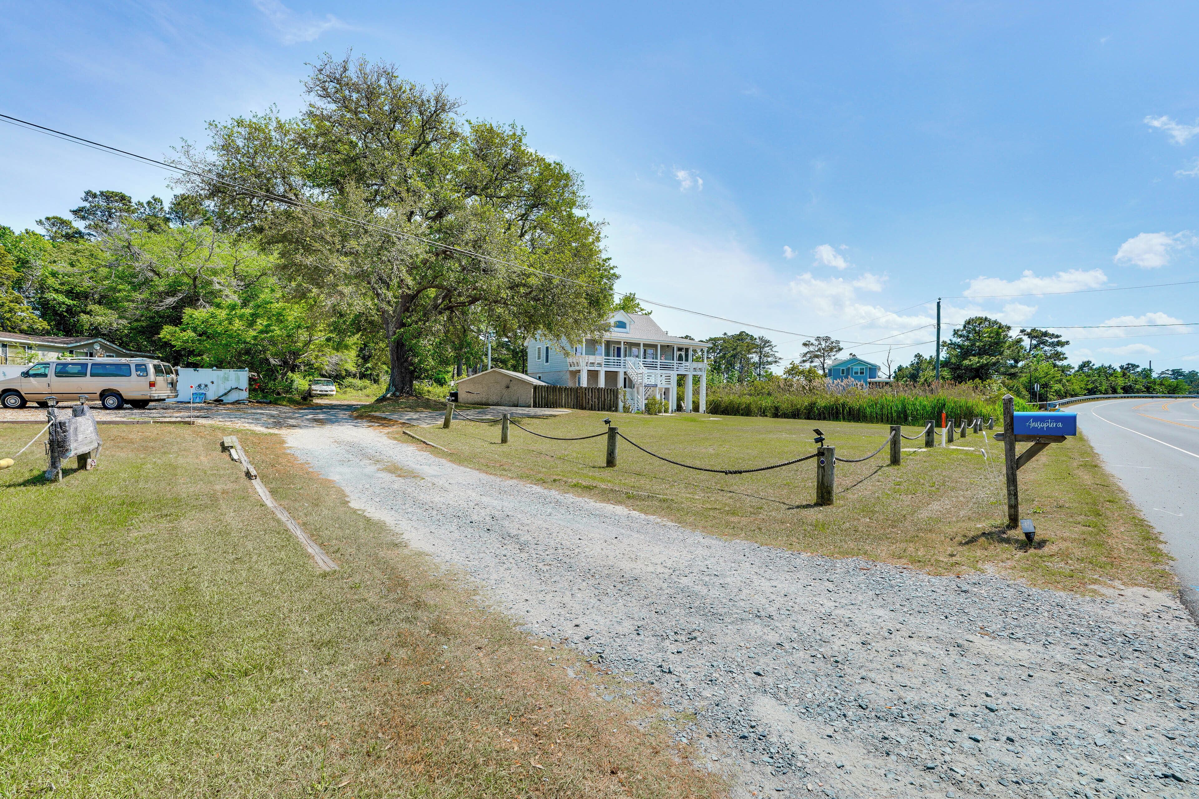 A gravel path leading to a house with a porch, a mailbox, and a fence.