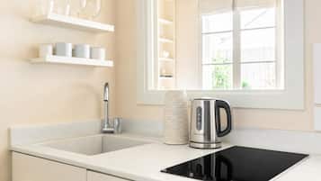 A kitchen with a double sink, a kettle, and a coffee maker on the counter.