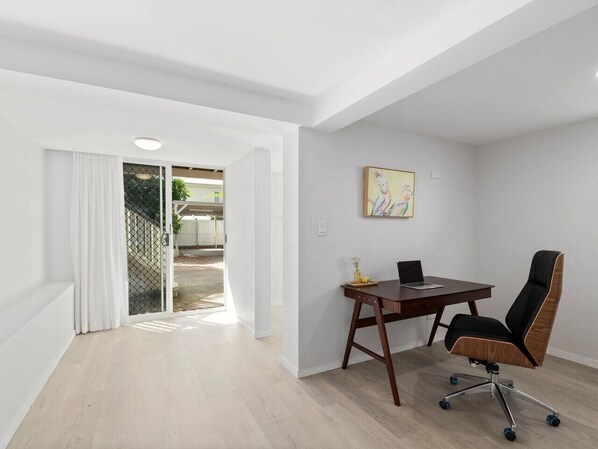 Habitación con escritorio, silla y vista al exterior.