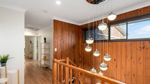 Un interior moderno con paneles de madera, una escalera de madera e iluminación colgante.