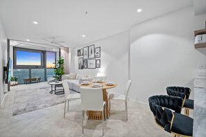 Sala de estar moderna com área de jantar, grandes janelas e vista para a cidade.