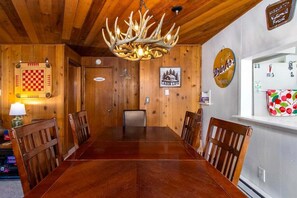 Uma sala de jantar de madeira com um candelabro, um tabuleiro xadrez e um letreiro com a inscrição 'Vida de Cabana'.