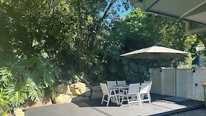 A patio with a table and chairs, surrounded by a stone wall and lush greenery.