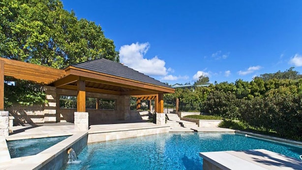 A swimming pool with a wooden pergola and stone steps.