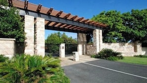 A stone building with a covered entrance, a gated driveway, and a well-maintained lawn.