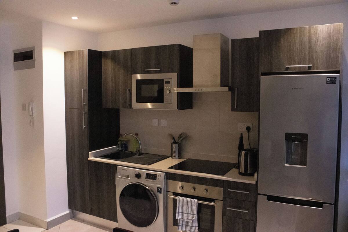 Eine moderne Küche mit Einbauwaschmaschine, Backofen, Mikrowelle und Kühlschrank.