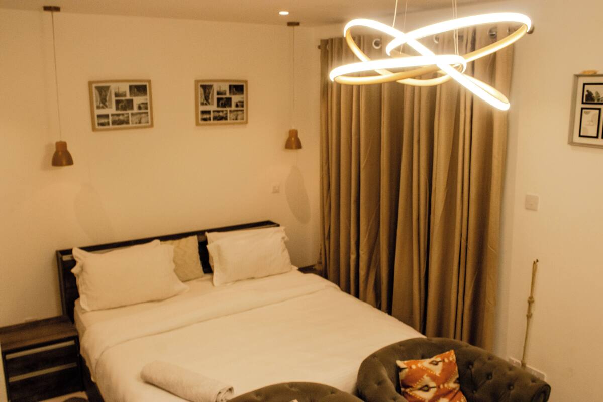 Ein Schlafzimmer mit einem Bett, Vorhängen und zwei an der Wand befestigten Bilderrahmen.