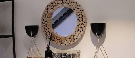 A wooden shelf with a mirror, two black vases, and a patterned box.