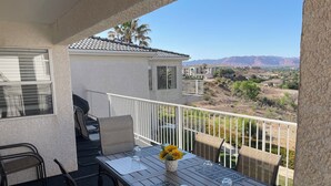 A balcony with a table set for two, a chair, and a view of a desert landscape. - Best View! 6 Pools & 4 Hot Tubs! Waterslides! Sport Courts! Remodeled! Location! (St. George)
