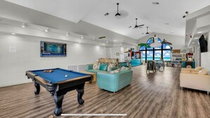 A pool table, a blue sofa, and a white couch in a room with wooden flooring and white walls. - Best View! 6 Pools & 4 Hot Tubs! Waterslides! Sport Courts! Remodeled! Location! (St. George)