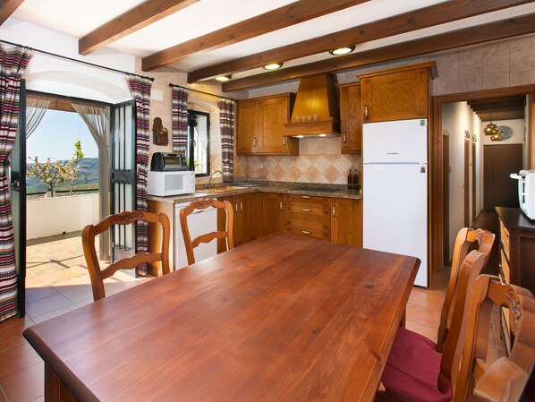 Eine Küche mit Holzausstattung, einem weißen Kühlschrank und einem Esstisch mit Stühlen.