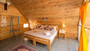 Ein Zimmer mit Holzwänden, einem Bett, Nachttischen, einer Leiter und einem Teppich.