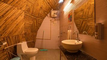 A bathroom with a wooden ceiling, a toilet, a sink, and a mop.