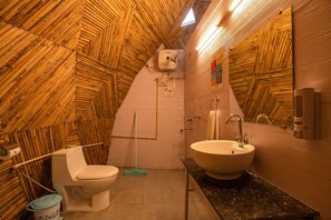 A bathroom with a wooden ceiling, a toilet, a sink, and a mop. - goSTOPS Dehradun Maldevta (Dhanaulti)