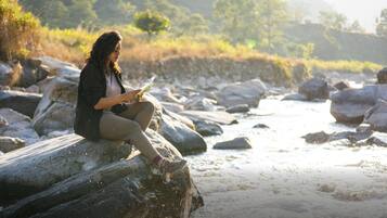 A person sitting on a rock by a river.