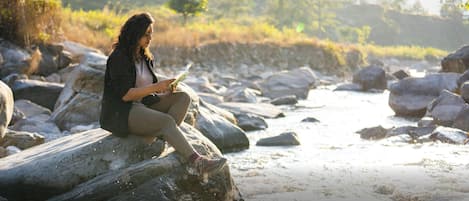 A person sitting on a rock by a river.