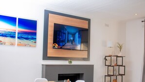 Un comedor moderno con una mesa de vidrio, sillas blancas y una chimenea.