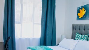Una habitación de hotel con cama, escritorio y ventana con cortinas.