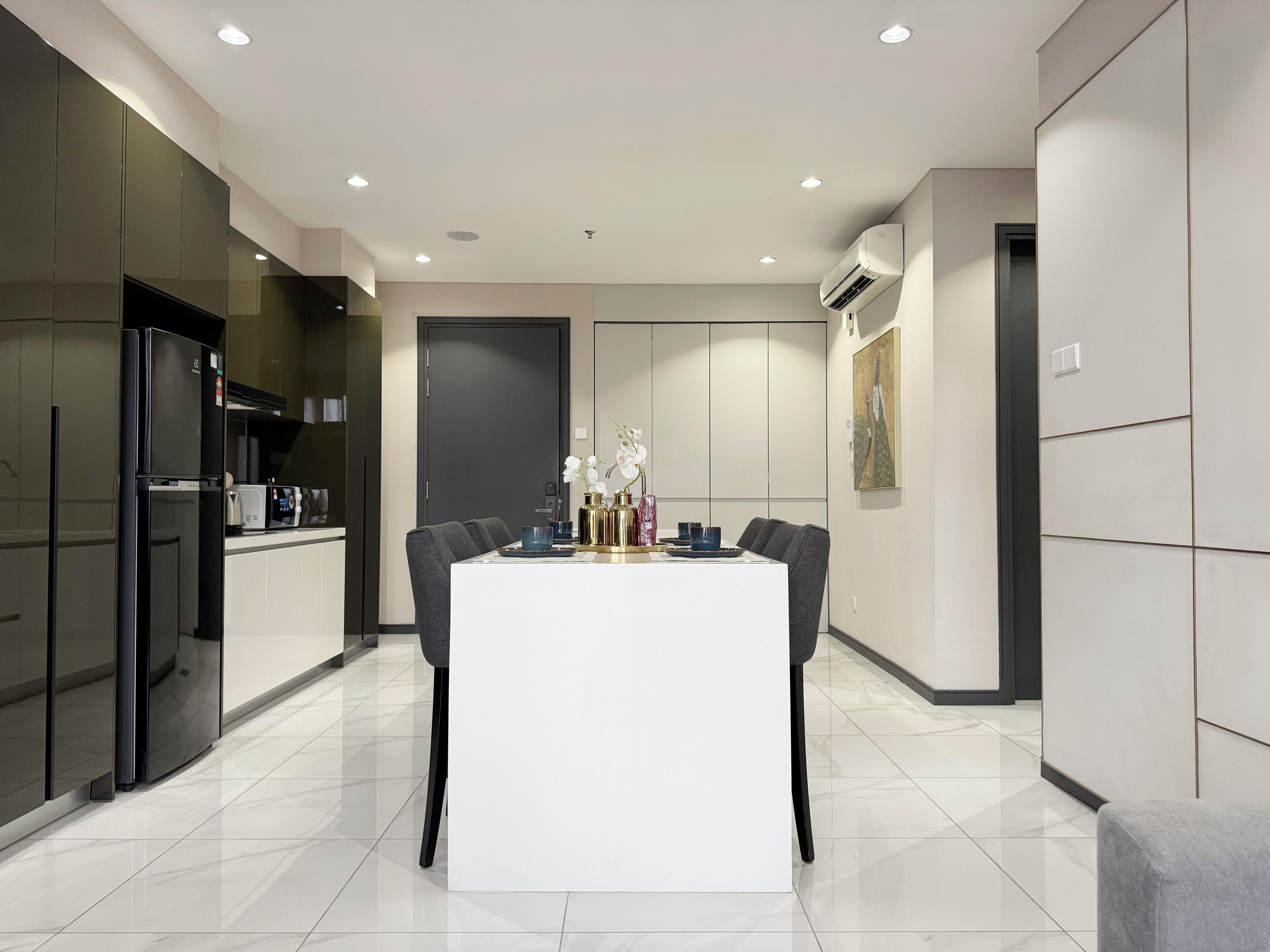 A modern kitchen with a central island, dark cabinetry, and recessed lighting.